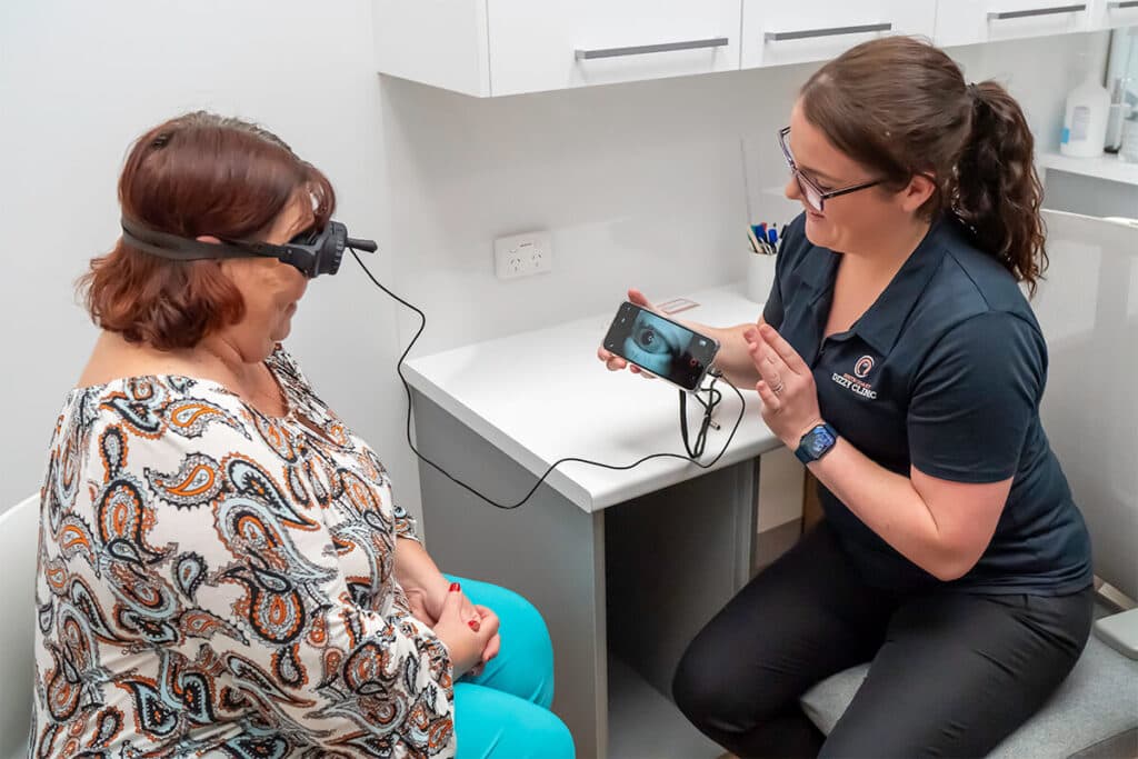 A Dizzy Clinics physiotherapist showing a patient her eye movements on a screen while the patient wears infrared video goggles